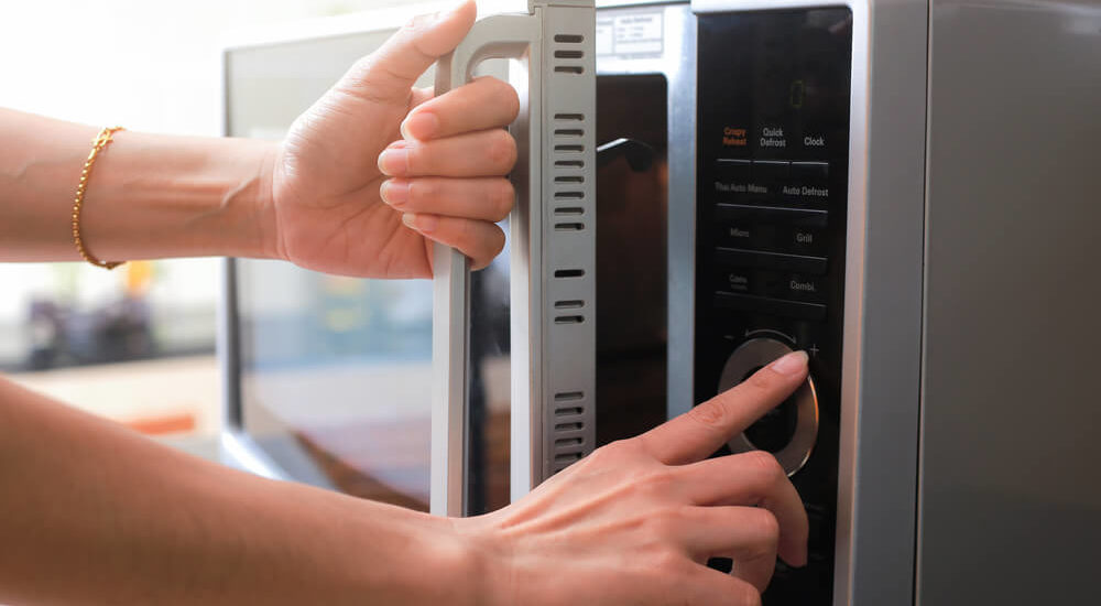 Woman's Hands Closing Microwave Oven Door And Reheating Food Safely in microwave